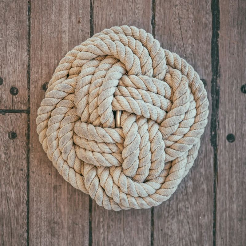 Un nœud décoratif en cordage clair posé sur un pont en teck