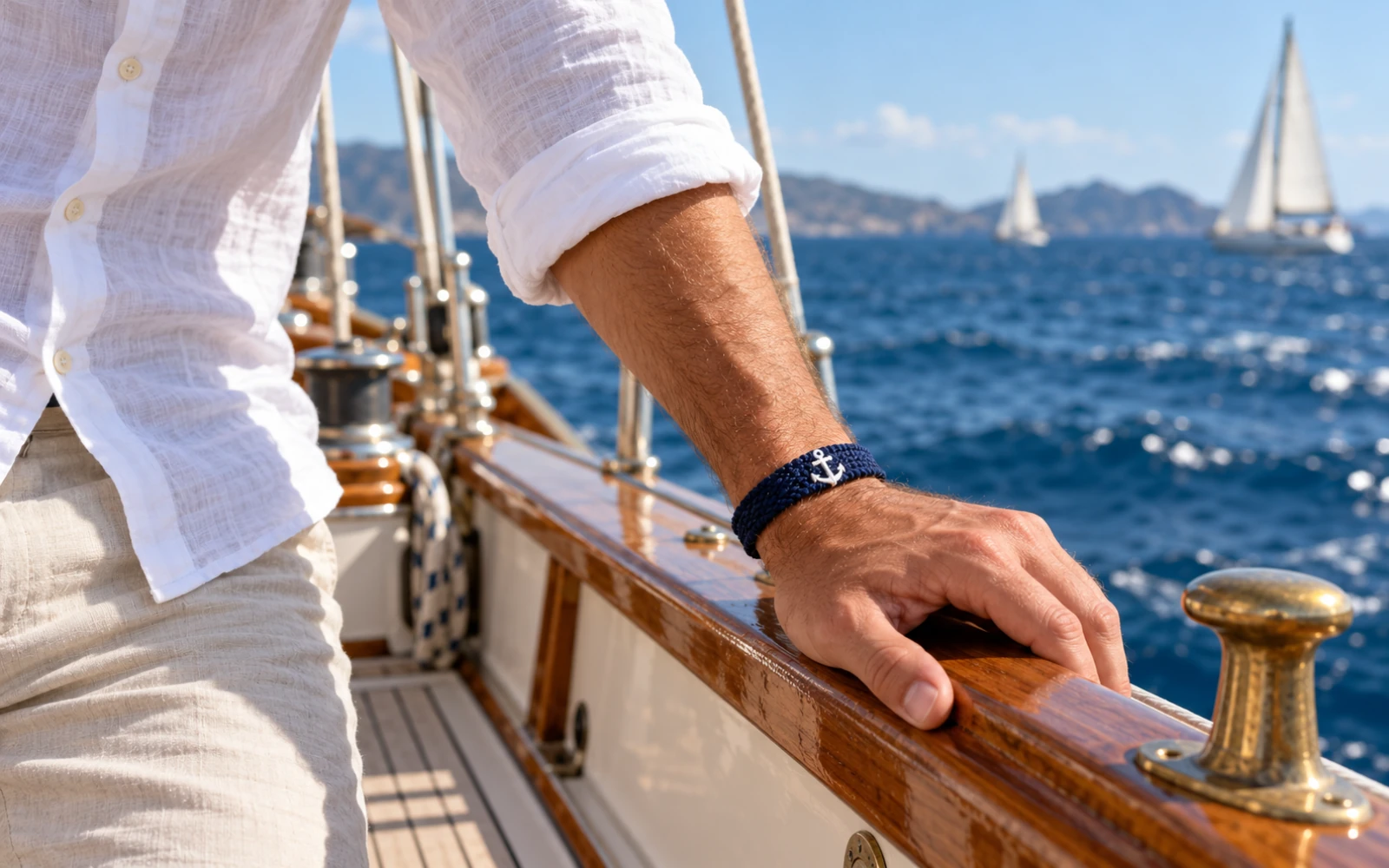 Homme en chemise blanche portant un bracelet bleu marine sur le pont d’un voilier