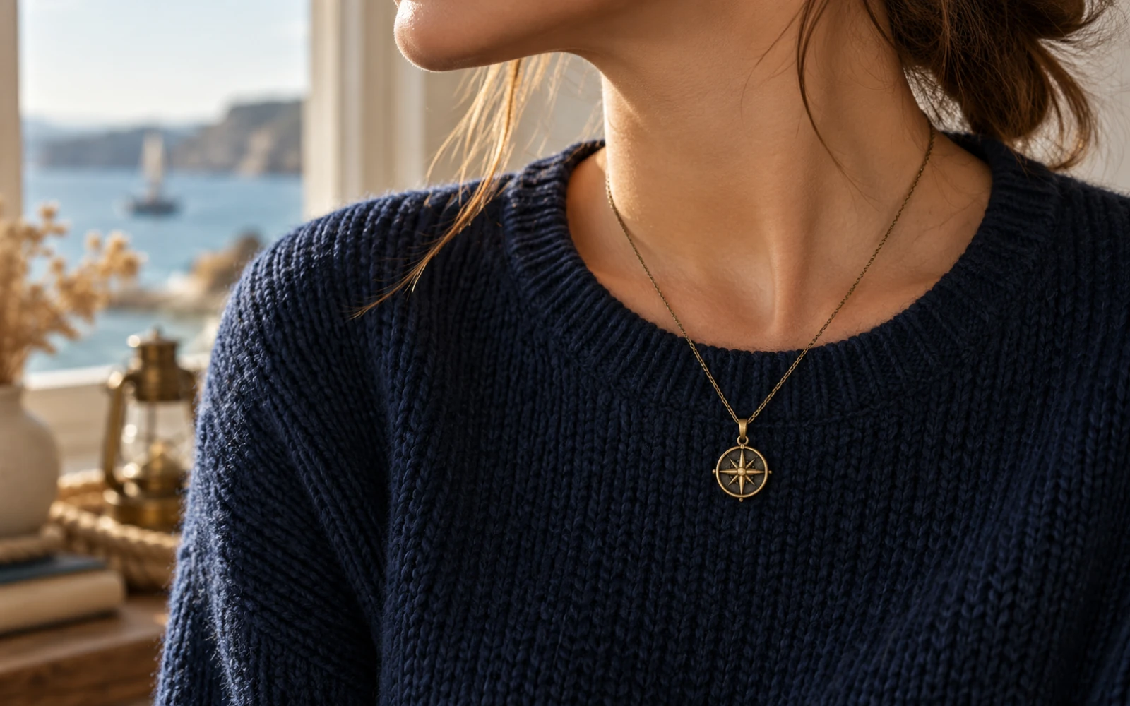 Gros plan sur un collier à pendentif boussole porté sur un pull marine