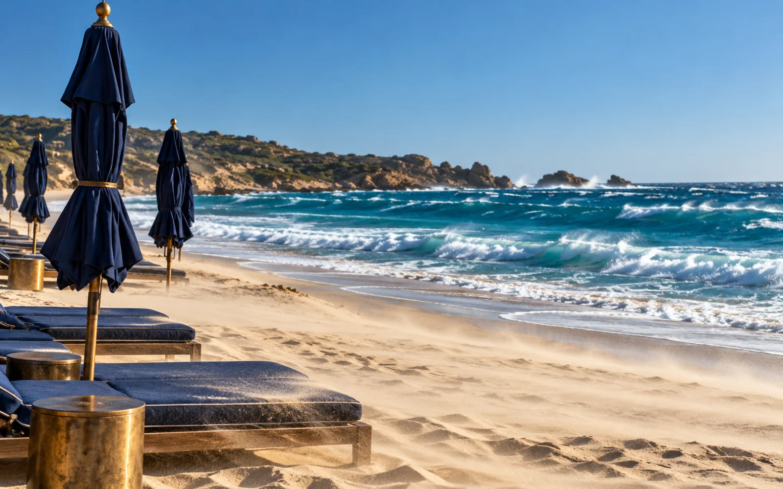 Plage presque vide avec des parasols couchés par le vent et une mer dégagée