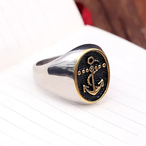 Bague vintage ancre dorée sur noir, vue de face sur un cahier