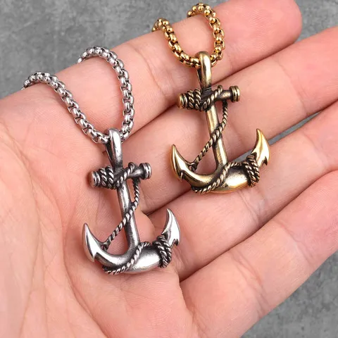 Collier pendentif ancre et cordage, pendentifs argent et or tenus dans la main, pour juger de la taille